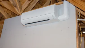Wall-mounted. ductless mini split indoor unit in unfinished space.