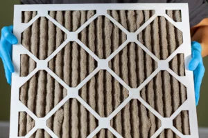 Dirty HVAC air filter being held for inspection or replacement during routine maintenance. Best for blogs about dirty air filter symptoms, how often to change your HVAC filter, clogged filter warning signs, poor airflow and dirty filters, indoor air quality issues, and furnace/AC maintenance.