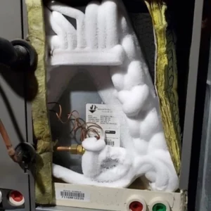 Close-up of ice buildup on indoor HVAC components and refrigerant lines inside an air handler or evaporator coil compartment. Best for blogs about frozen AC coils, evaporator coil freezing, AC not cooling, airflow problems, refrigerant issues, frozen HVAC unit troubleshooting.