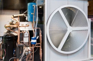 Cutaway view of heat pump equipment showing internal components, copper refrigerant lines, and the outdoor fan assembly. Best for blogs about heat pump components, AC system components, how a heat pump works, compressor and refrigerant system basics, heat pump repair.