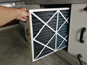 How often to change HVAC filter: hand removing air filter from a commercial or whole-house HVAC unit